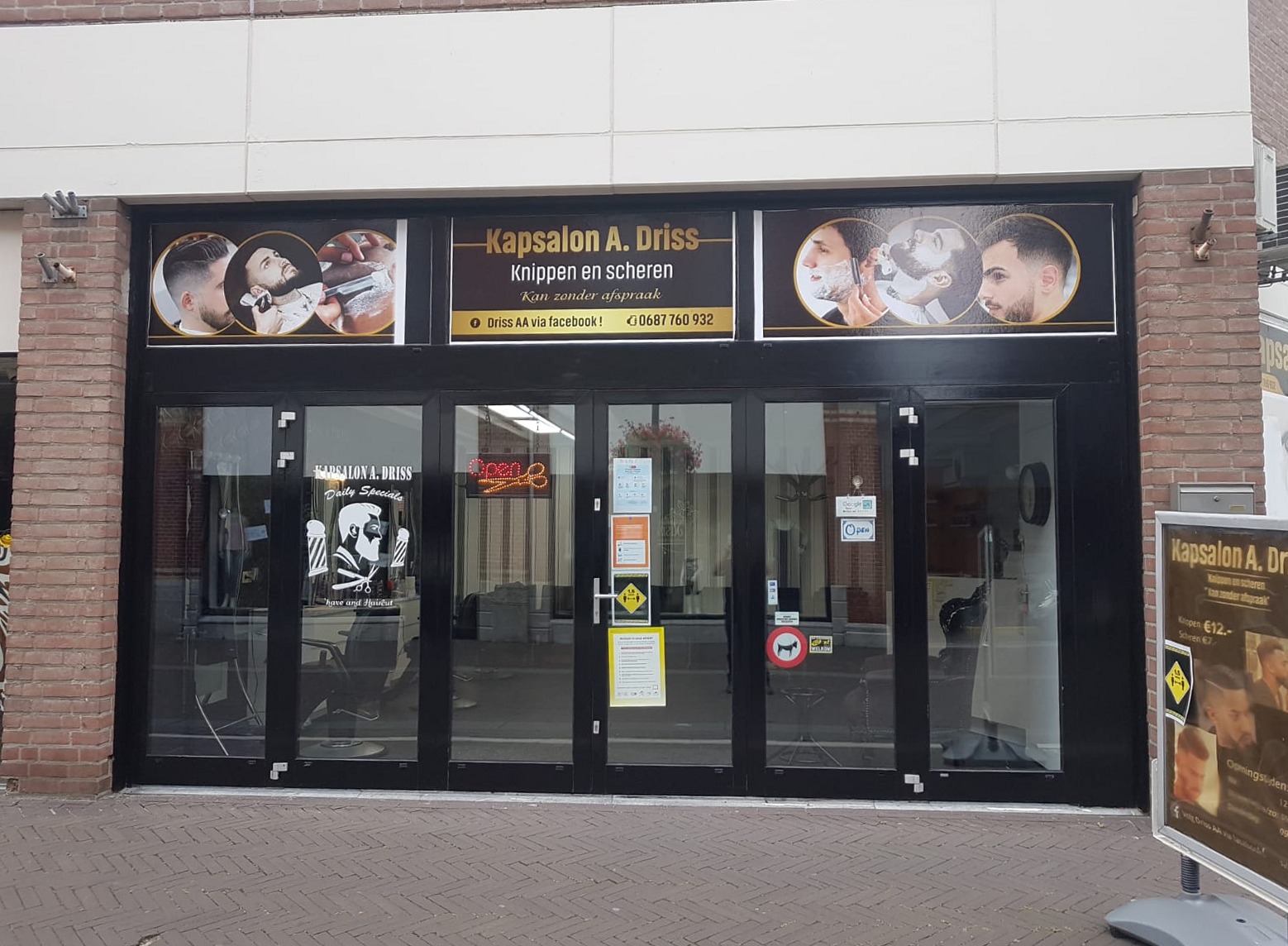 De winkelpui van Kapsalon Driss met het zwarte bord Kapsalon A. Driss, knippen en scheren