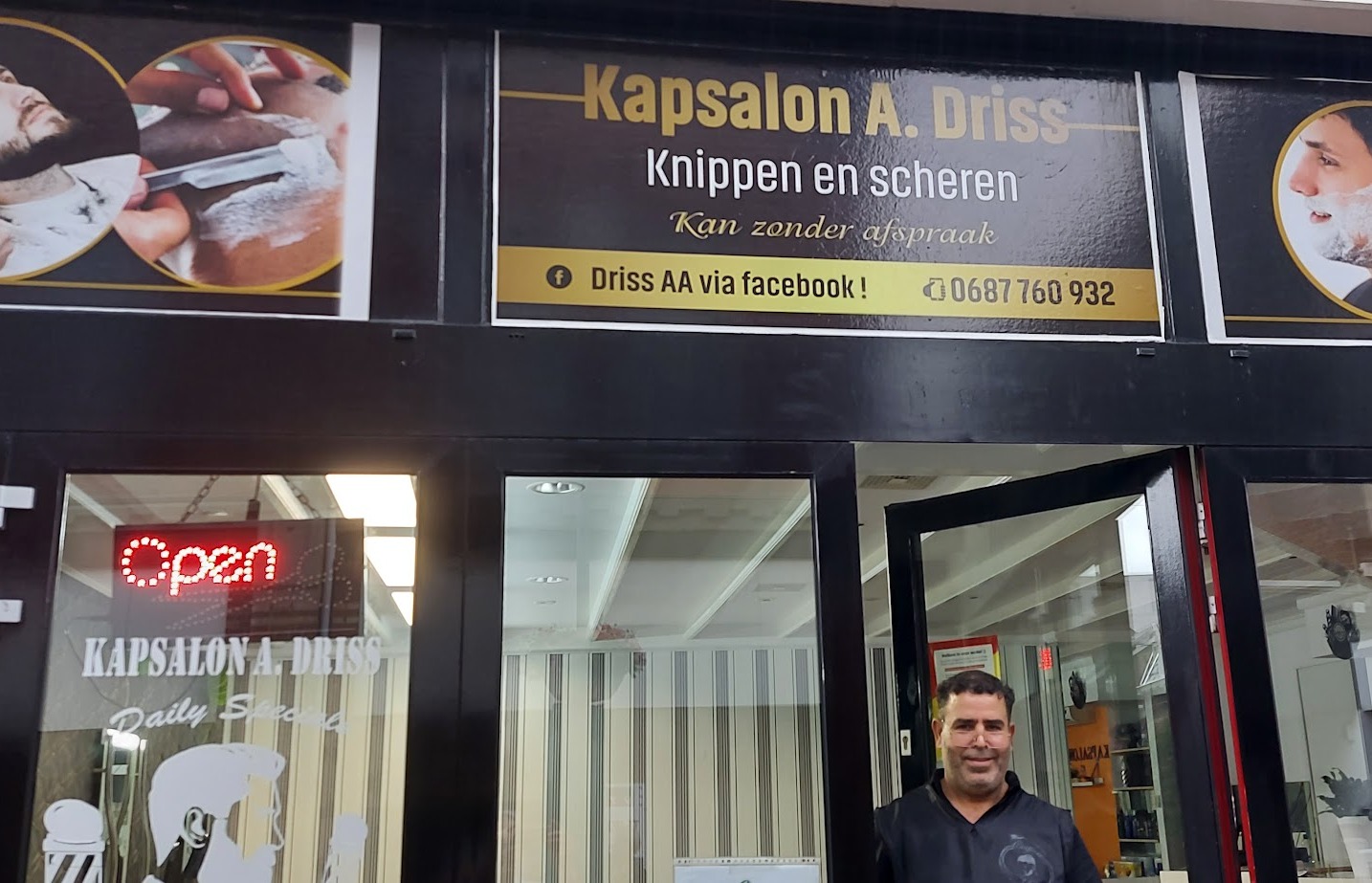 De gevel van Kapsalon Driss aan de Kerkstraat 18 met het zwart-gouden bord en een man in de deuropening